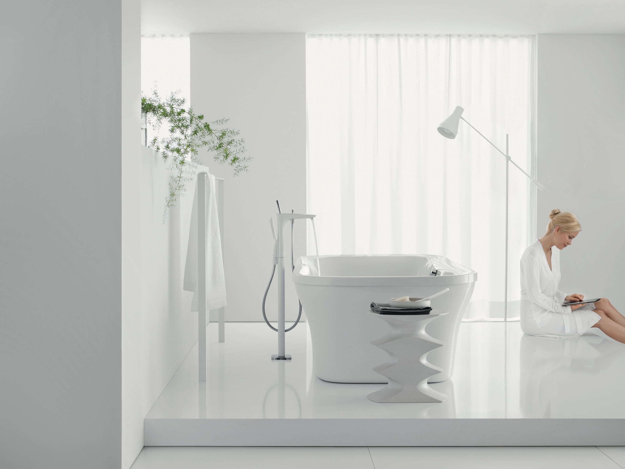 woman sitting in modern clean white bathroom with tub and lamp